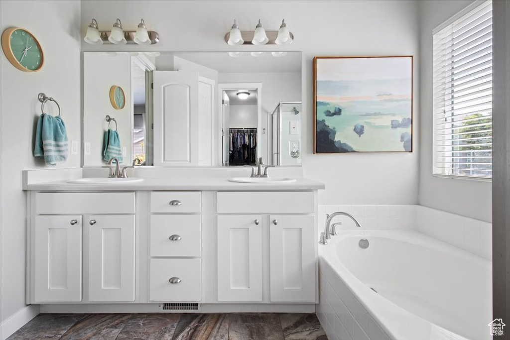 Bathroom with double vanity, tiled bath, and tile floors