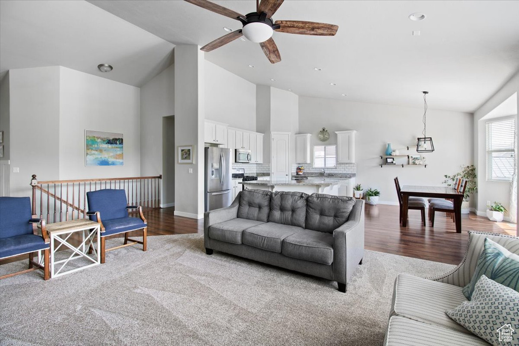 Carpeted living room with high vaulted ceiling and ceiling fan