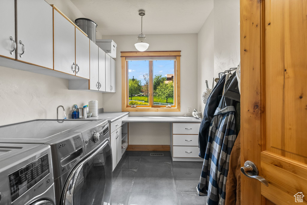 Washroom featuring cabinets, dark tile flooring, and separate washer and dryer