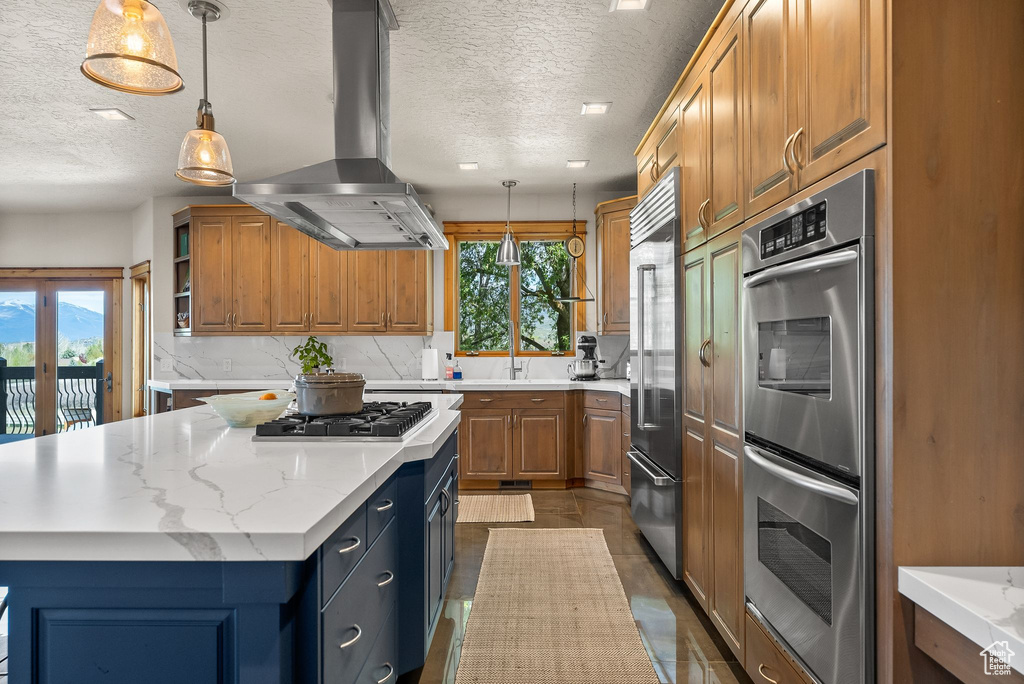 Kitchen with island range hood, tasteful backsplash, a center island, appliances with stainless steel finishes, and pendant lighting