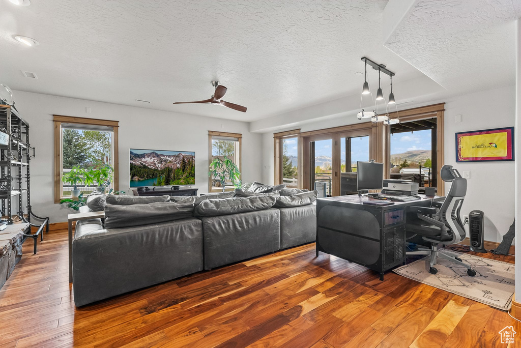 Living room with ceiling fan, french doors, a textured ceiling, and hardwood / wood-style flooring