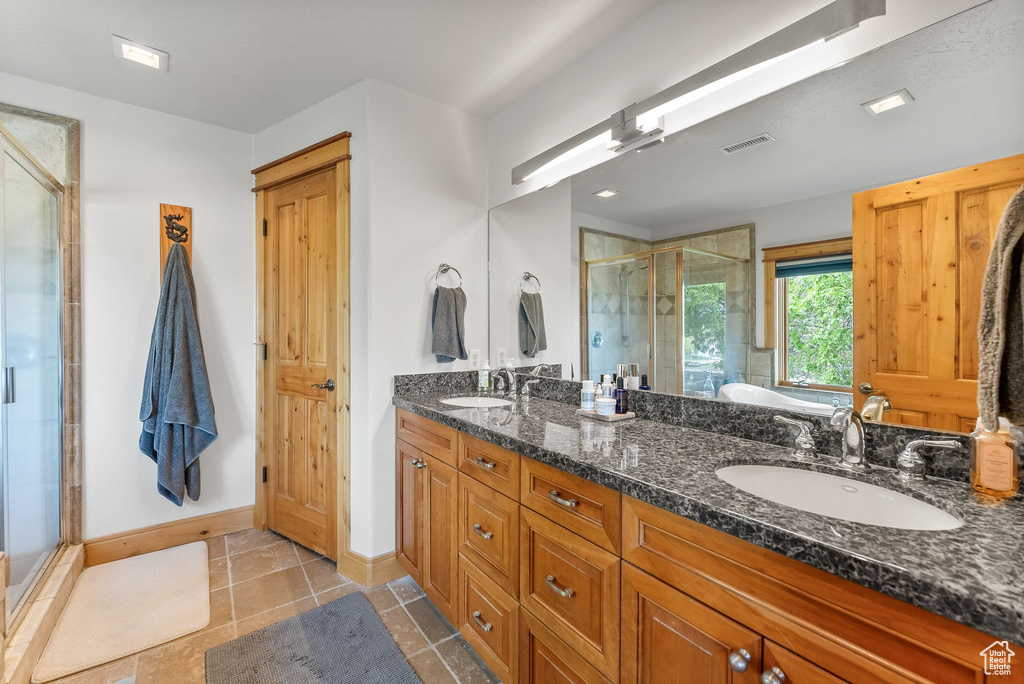 Bathroom featuring tile floors, an enclosed shower, and dual bowl vanity