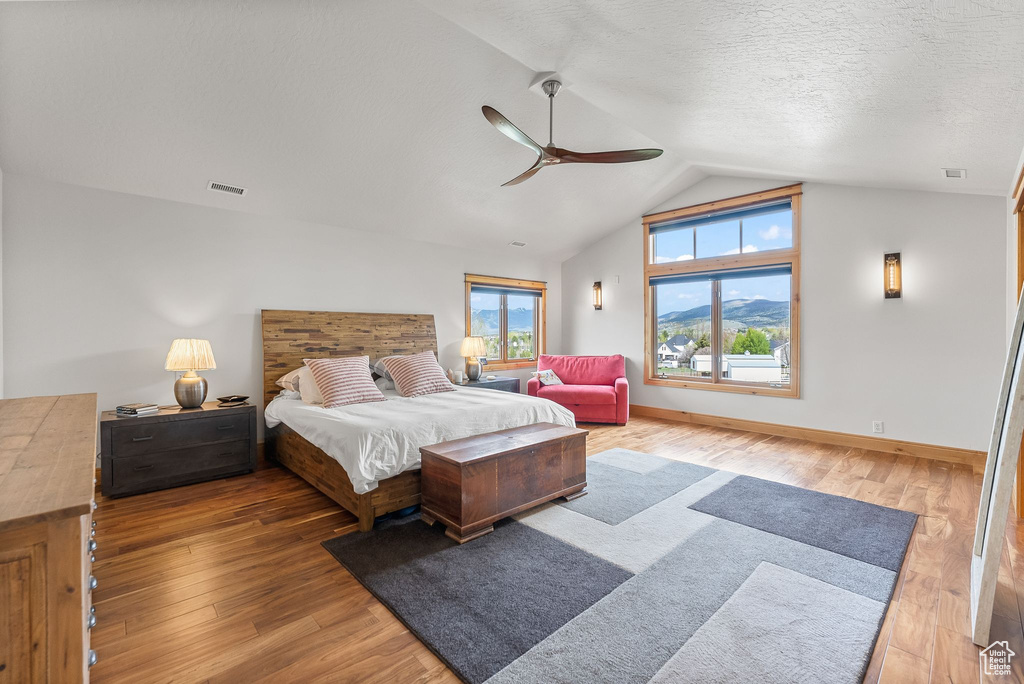 Bedroom featuring ceiling fan, vaulted ceiling, a textured ceiling, and wood-type flooring