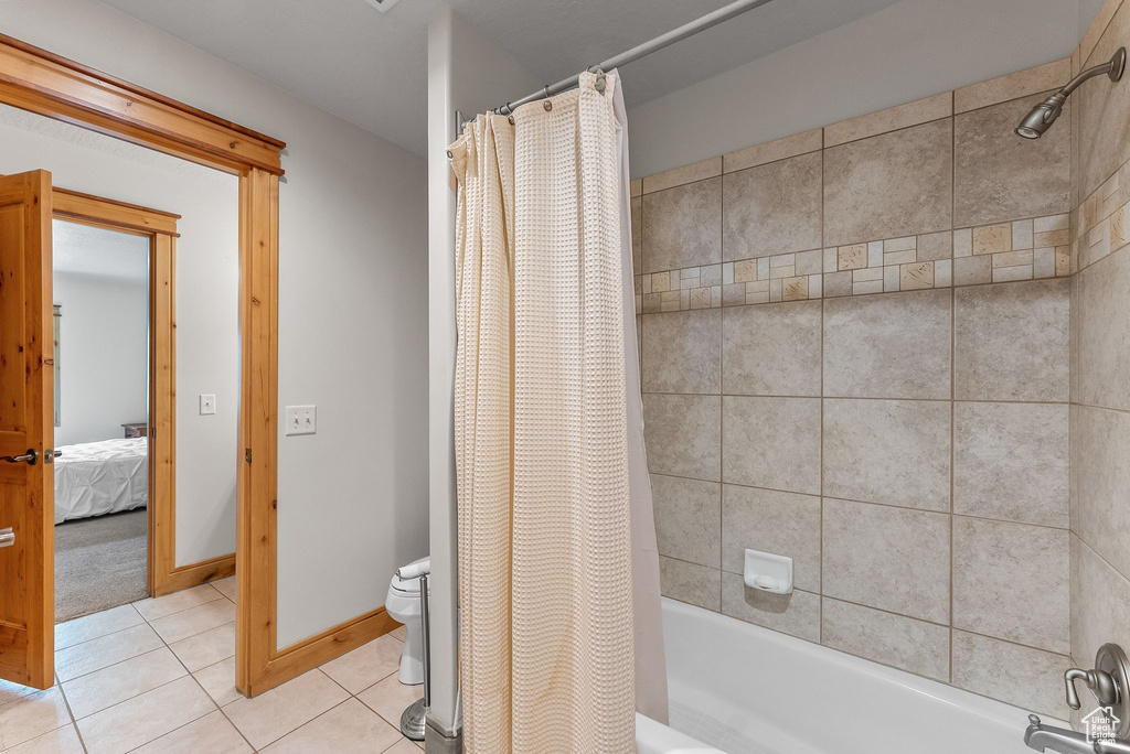 Bathroom with tile flooring, shower / bath combo, and toilet