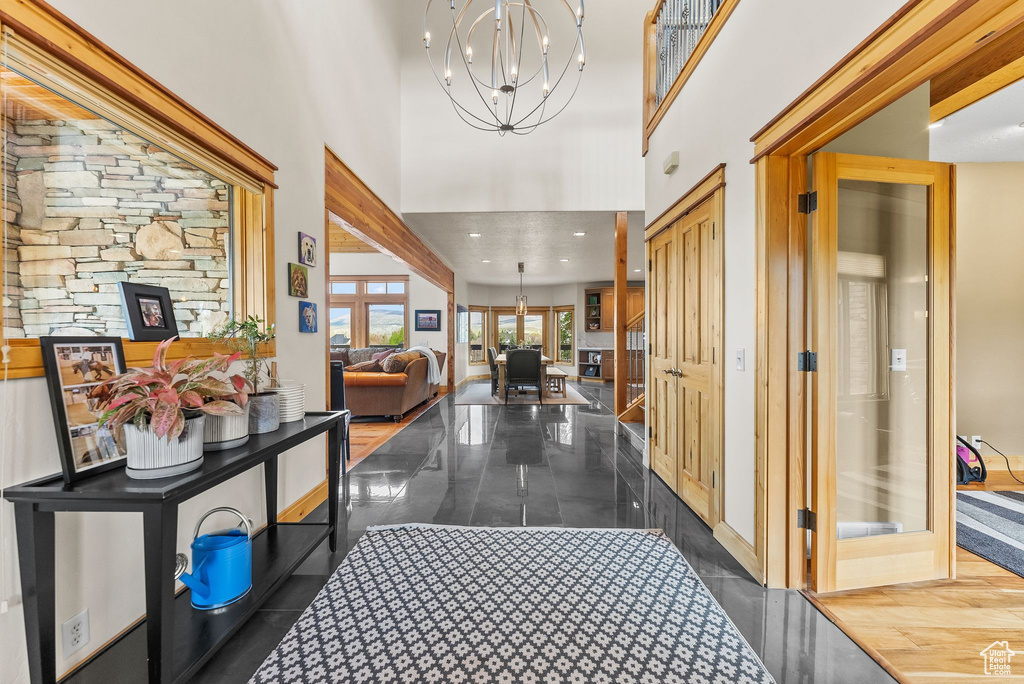 Hall featuring dark hardwood / wood-style floors, a towering ceiling, and a chandelier