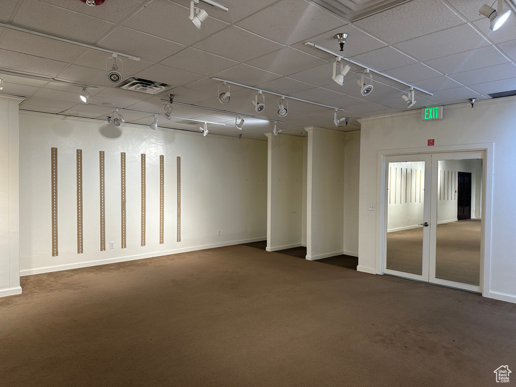 Empty room with french doors, track lighting, and dark colored carpet