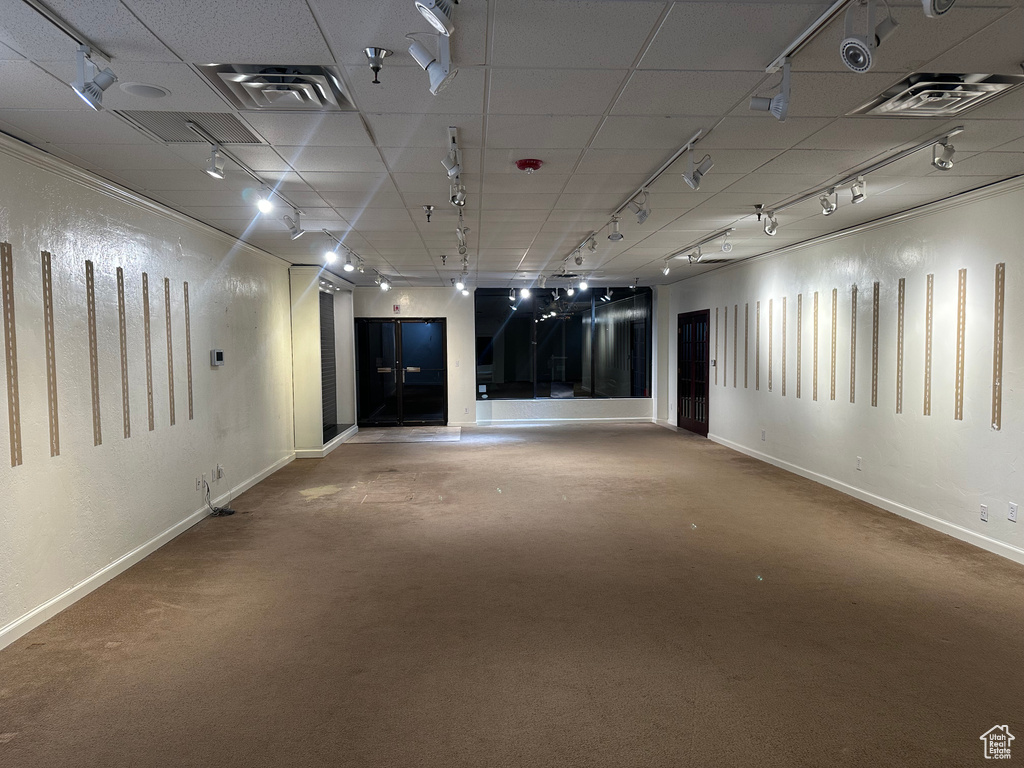 Carpeted empty room featuring rail lighting