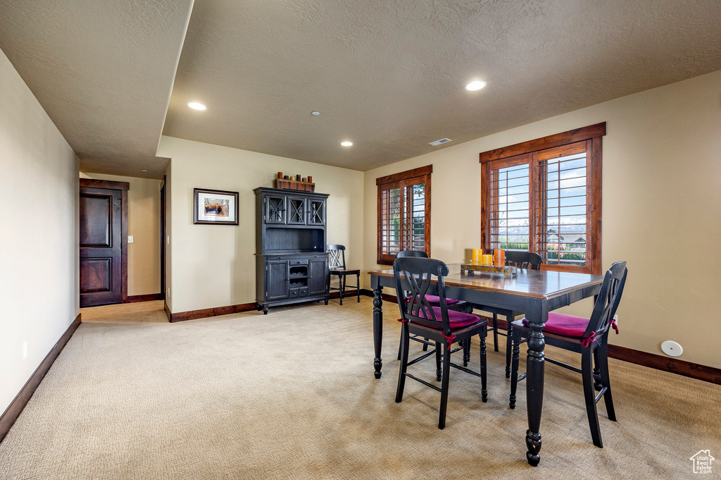 Dining room with light carpet and a textured ceiling