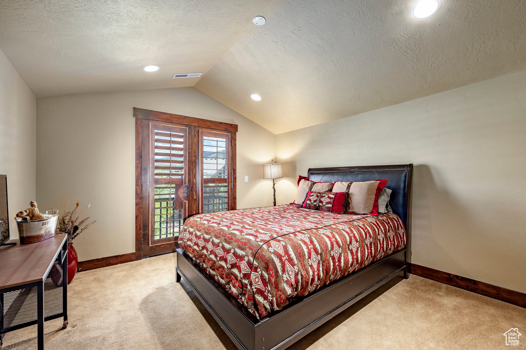 Bedroom with vaulted ceiling, carpet, and a textured ceiling