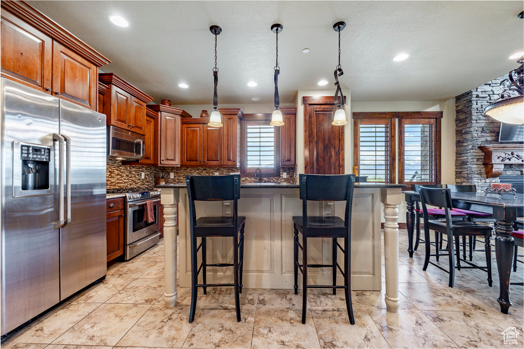 Kitchen with a wealth of natural light, backsplash, light tile floors, and stainless steel appliances