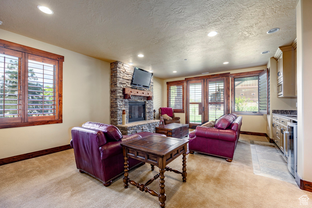 Carpeted living room with a textured ceiling, a fireplace, and plenty of natural light