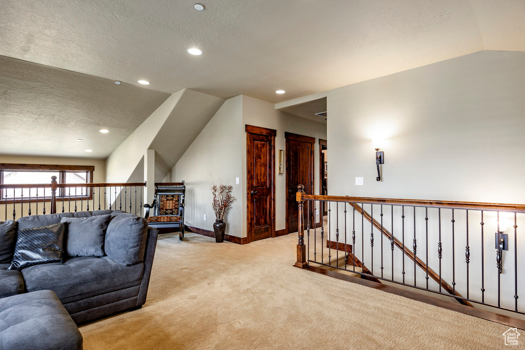 Carpeted living room featuring vaulted ceiling and a textured ceiling