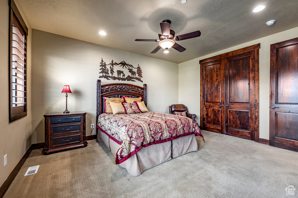 Carpeted bedroom featuring ceiling fan and a textured ceiling