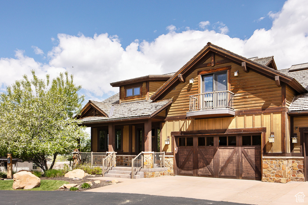 View of front of home featuring a garage and a balcony