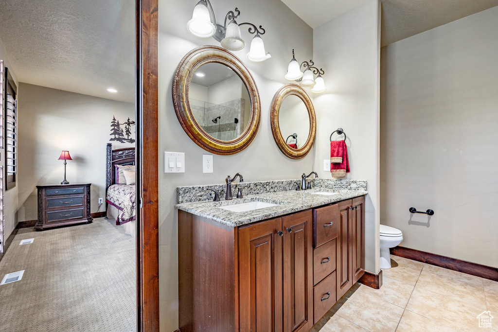 Bathroom featuring a textured ceiling, tile flooring, toilet, oversized vanity, and dual sinks