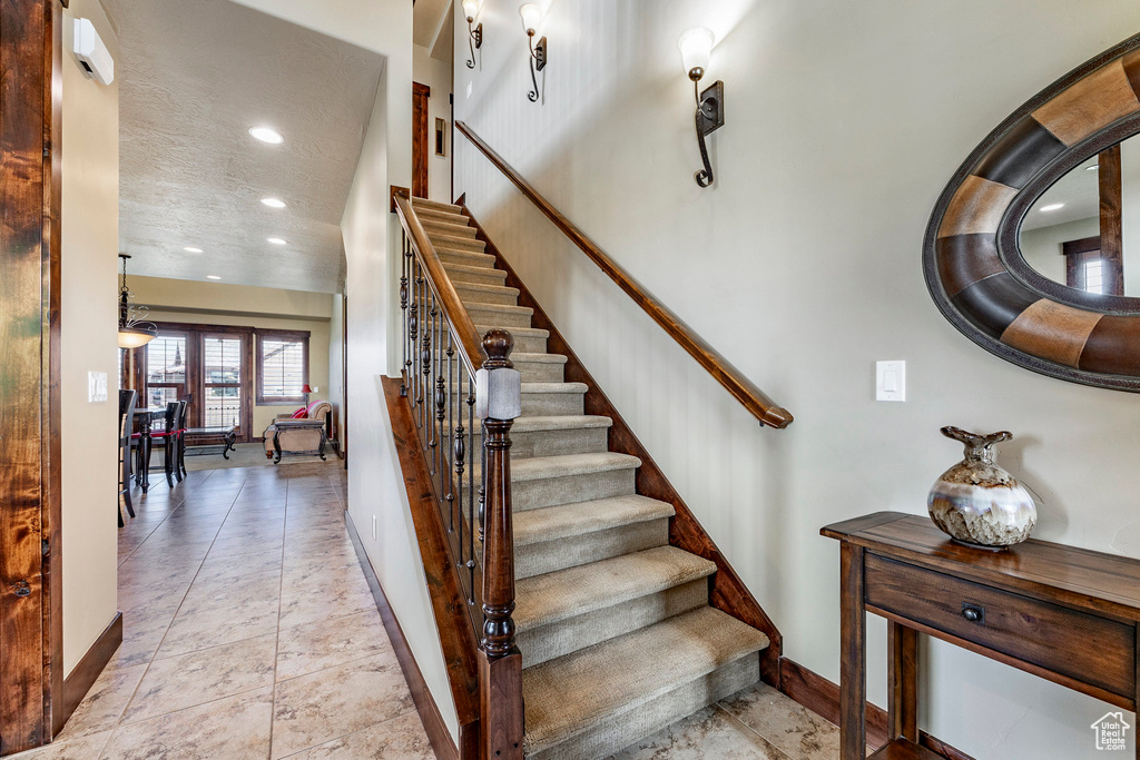 Stairs with tile floors, a textured ceiling, and a towering ceiling