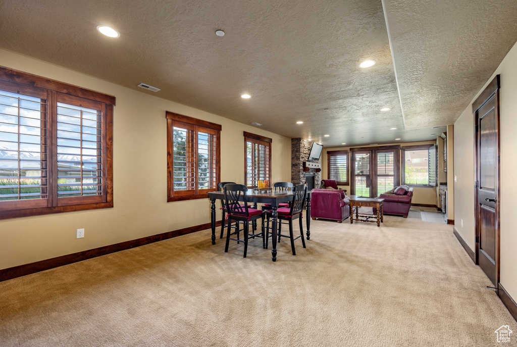 Dining space featuring brick wall, a textured ceiling, carpet floors, and a fireplace