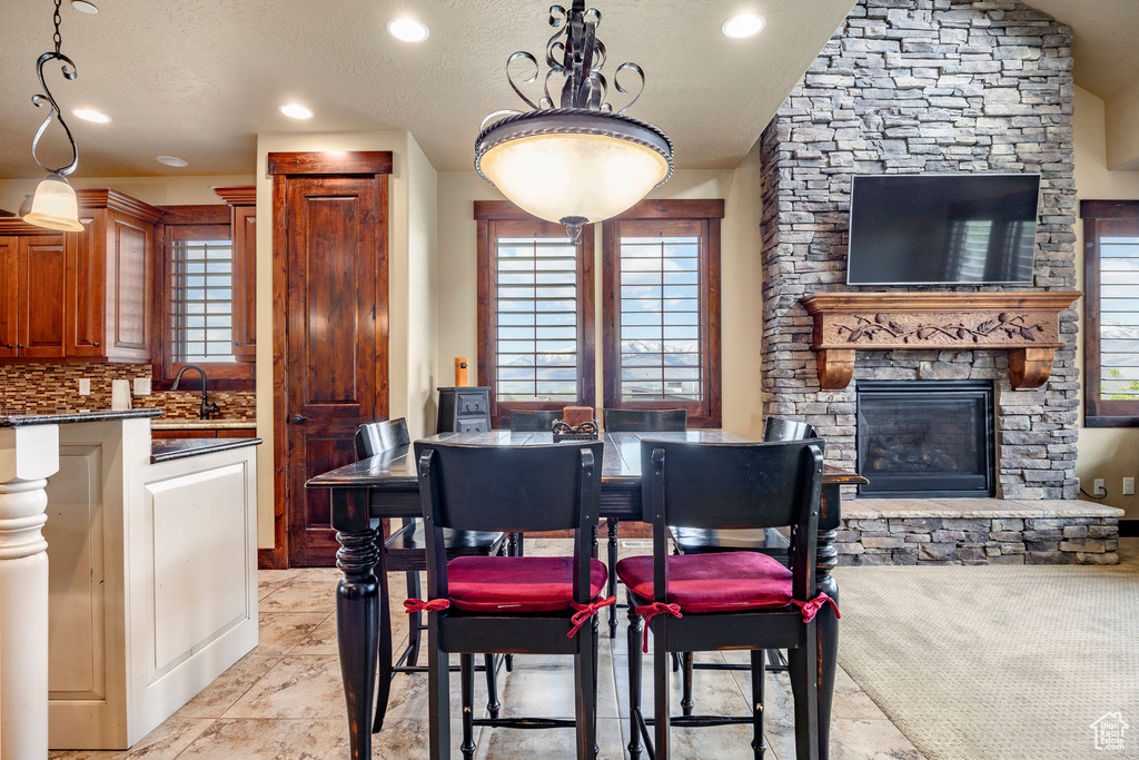 Dining space with sink, light tile flooring, a textured ceiling, and a fireplace