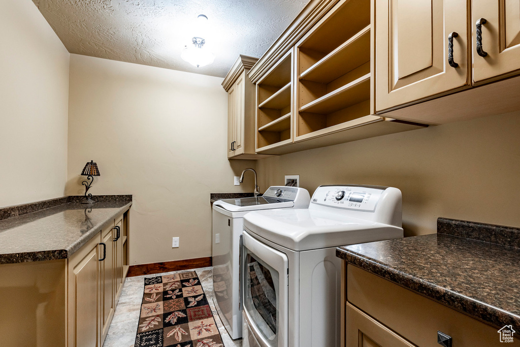 Washroom featuring washer and dryer, a textured ceiling, light tile flooring, and cabinets