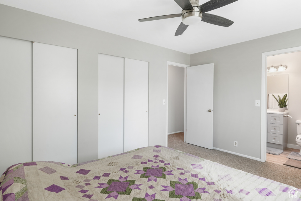 Bedroom with two closets, ceiling fan, light colored carpet, and connected bathroom