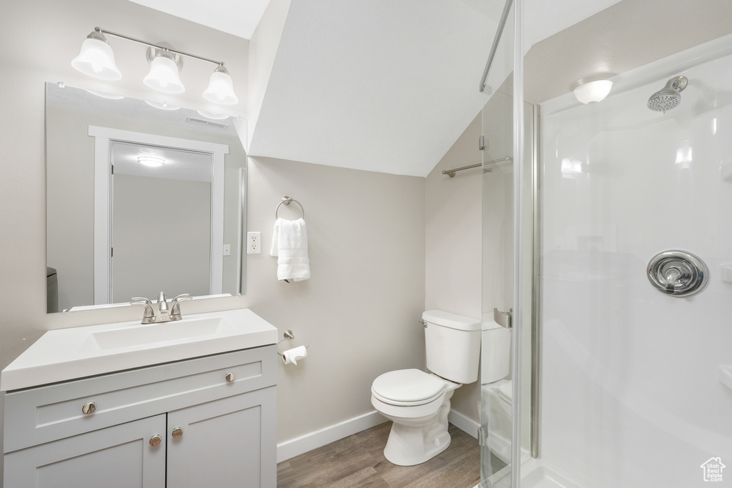 Bathroom with wood-type flooring, oversized vanity, toilet, and vaulted ceiling