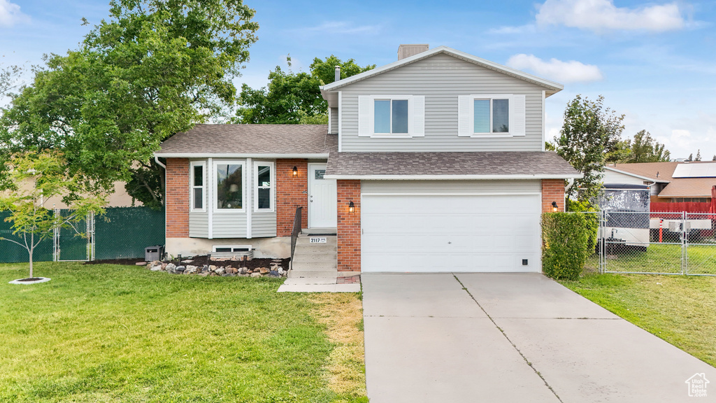 Tri-level home with central AC, a front lawn, and a garage