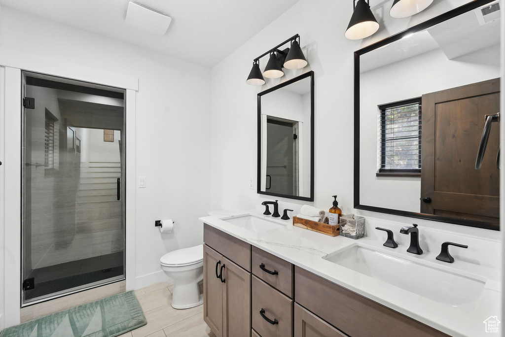 Bathroom with large vanity, double sink, toilet, and a shower with door