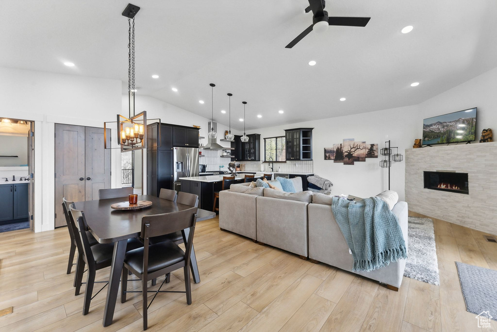 Dining area featuring ceiling fan with notable chandelier, light hardwood / wood-style flooring, and lofted ceiling