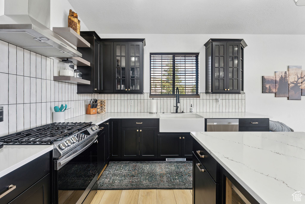 Kitchen featuring stainless steel appliances, sink, wall chimney exhaust hood, and tasteful backsplash