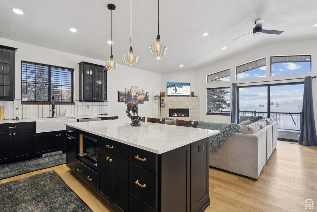 Kitchen featuring sink, hanging light fixtures, a center island, a fireplace, and a healthy amount of sunlight