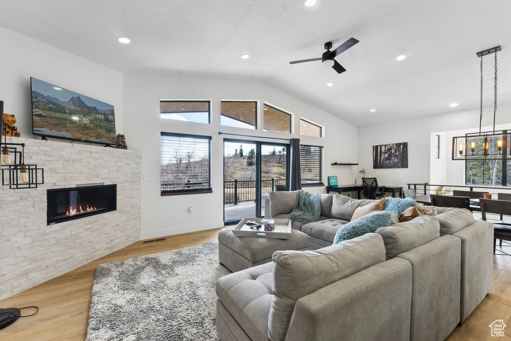 Living room with a wealth of natural light, a fireplace, light wood-type flooring, and ceiling fan