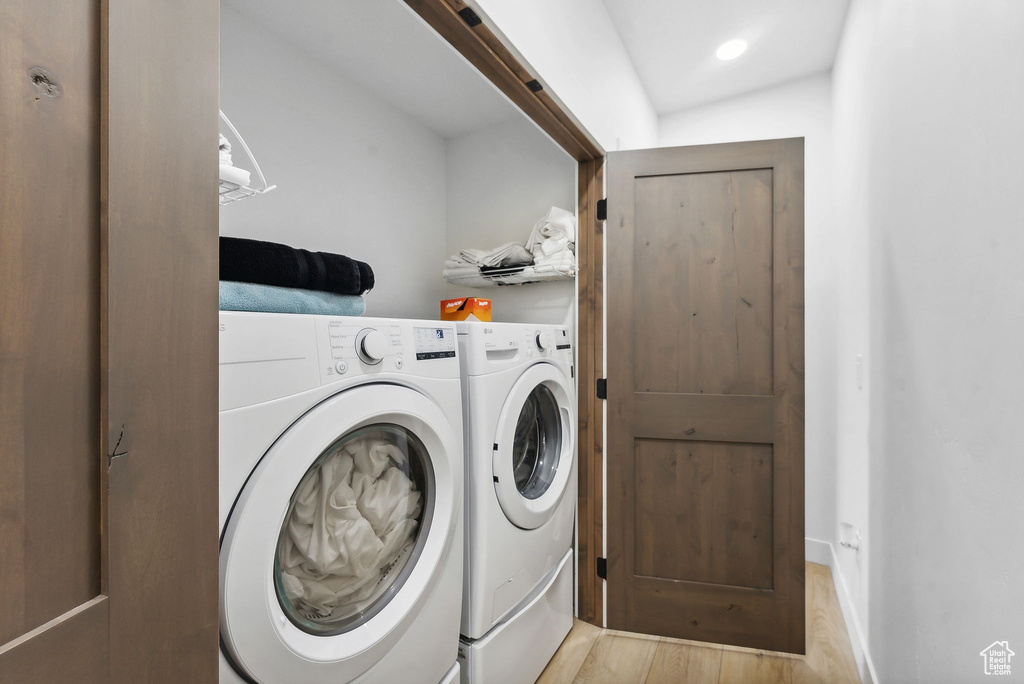 Washroom with washer and dryer and light wood-type flooring