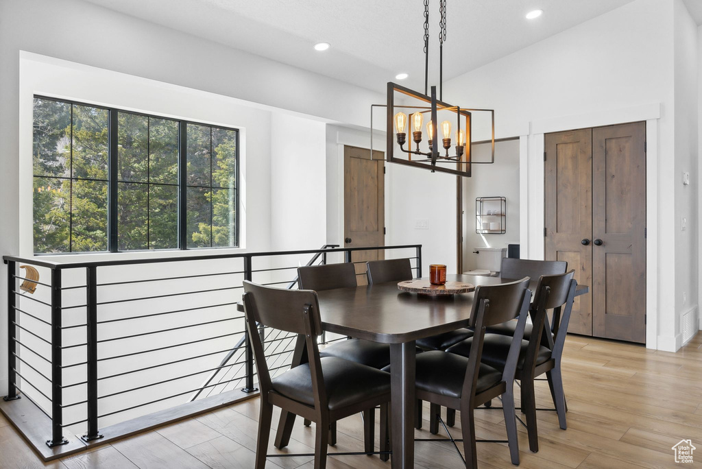 Dining room with a notable chandelier, vaulted ceiling, and light hardwood / wood-style flooring