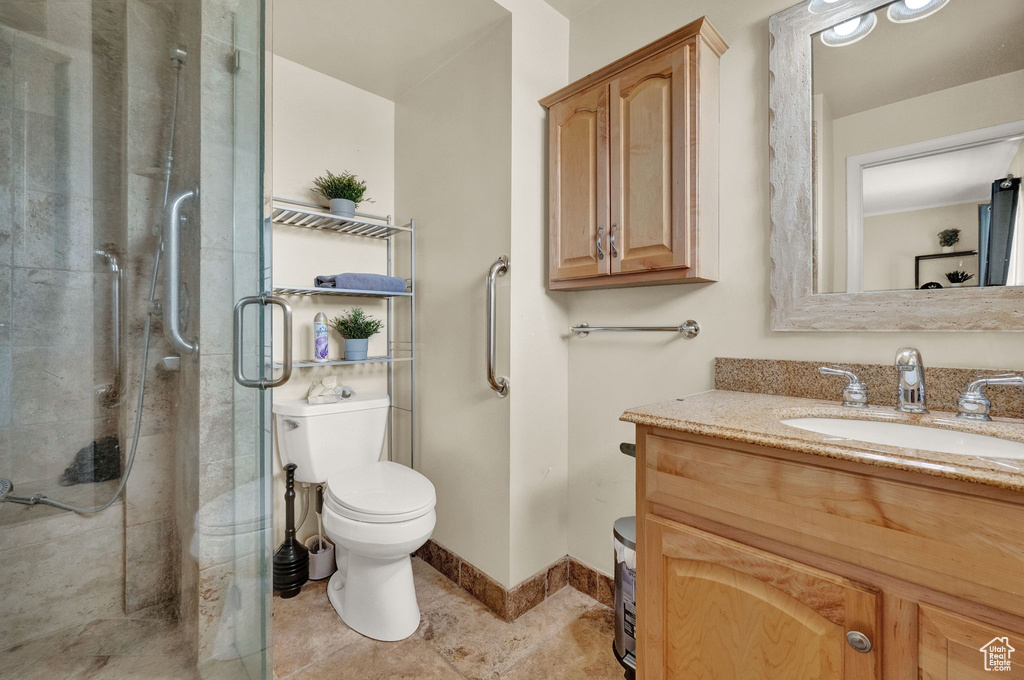 Bathroom with tile floors, a shower with door, oversized vanity, and toilet