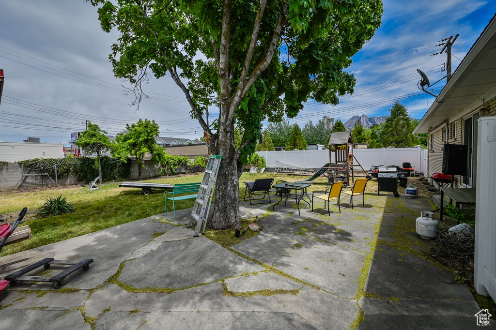 Exterior space featuring a playground, a patio area, and a trampoline