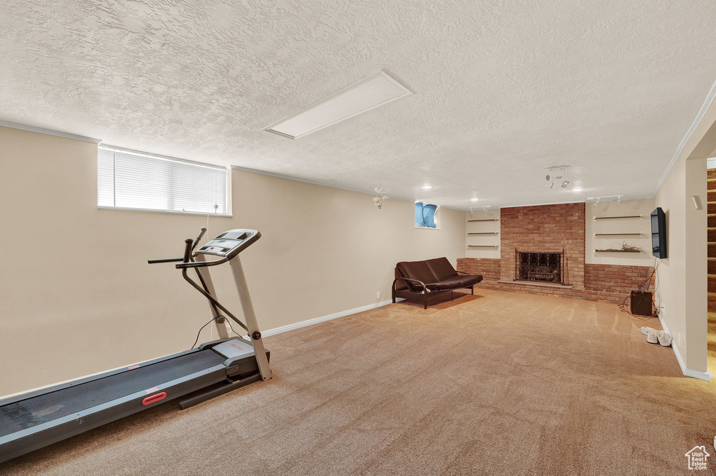 Workout area with carpet, a textured ceiling, brick wall, and a brick fireplace