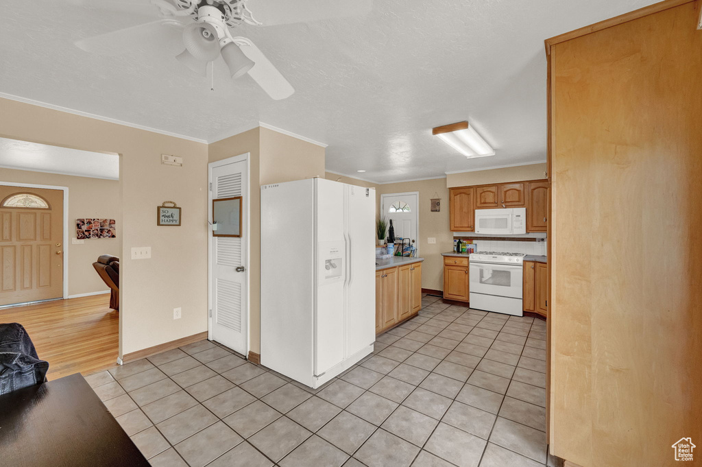 Kitchen with ceiling fan, crown molding, white appliances, and light tile floors