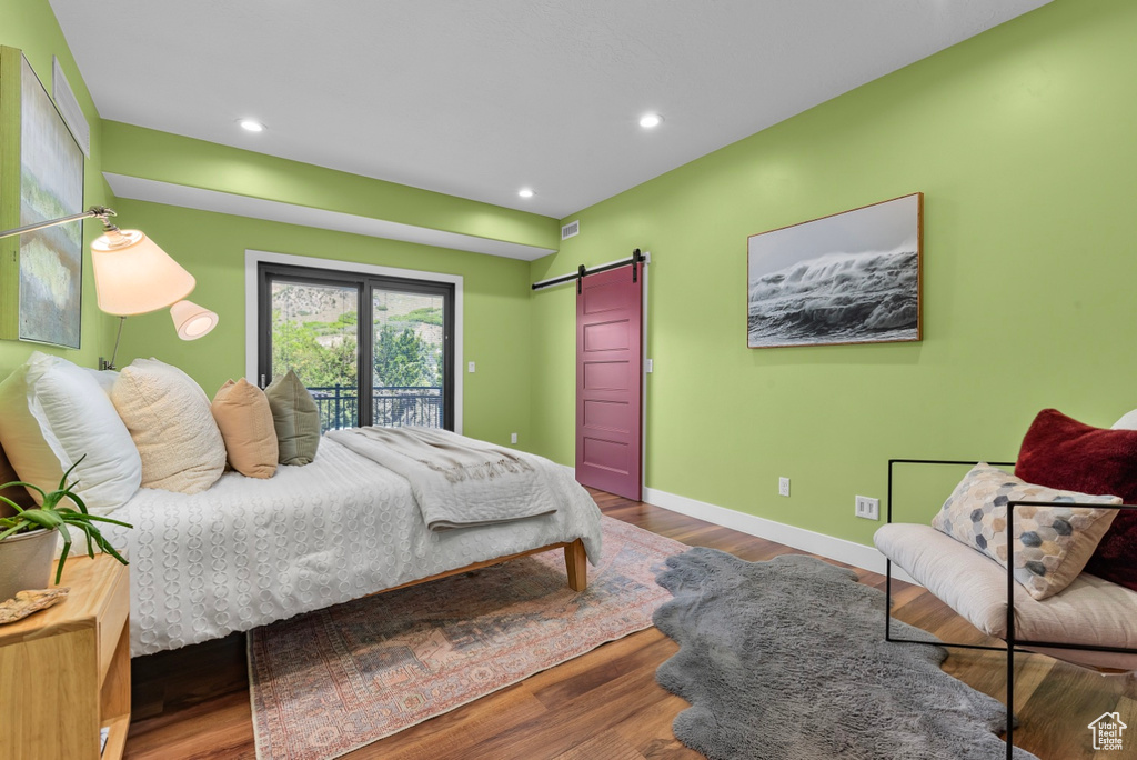 Bedroom featuring wood-type flooring, a barn door, and access to outside