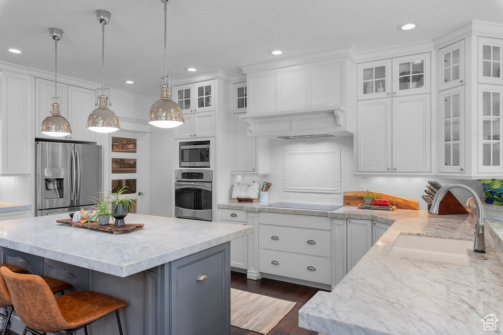 Kitchen with white cabinetry, stainless steel appliances, tasteful backsplash, and sink