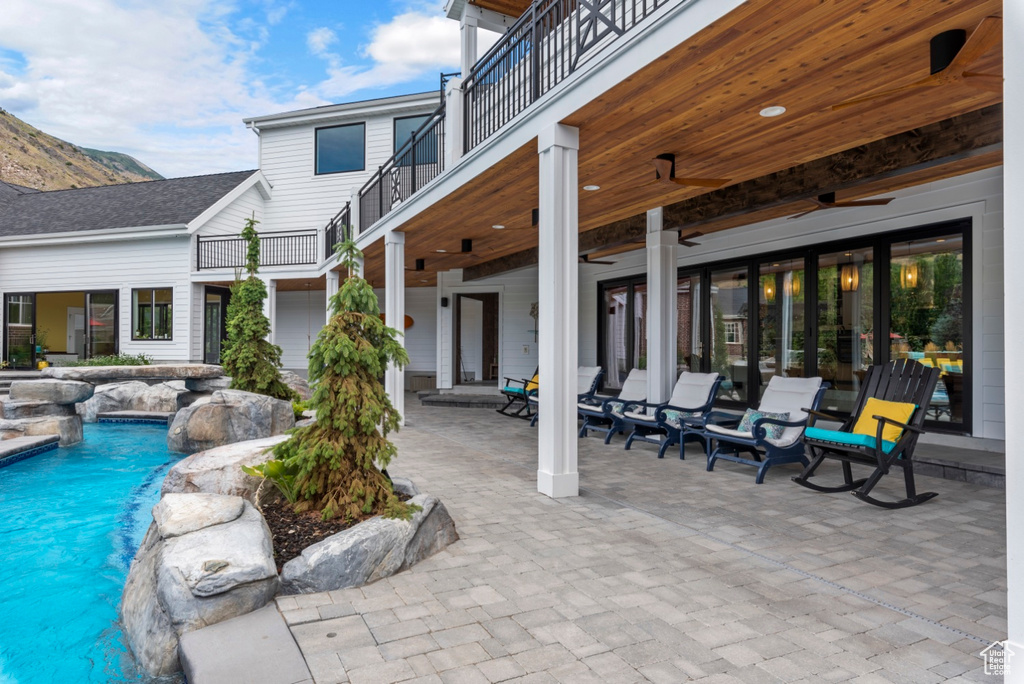 View of patio featuring pool water feature, a balcony, and ceiling fan