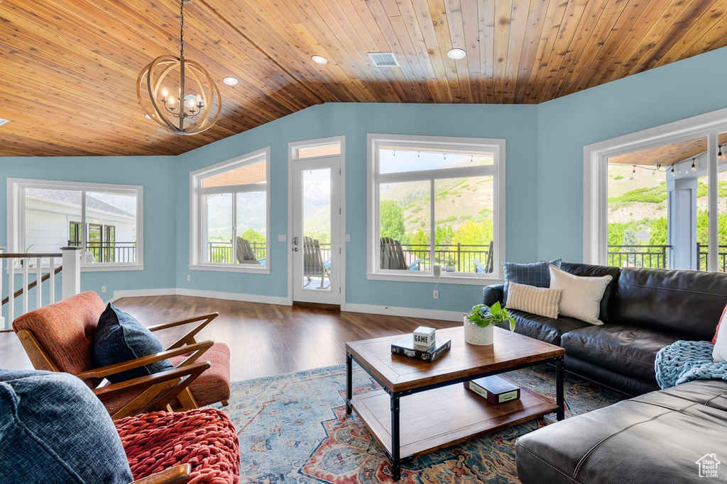 Living room featuring a notable chandelier, wooden ceiling, a wealth of natural light, and hardwood / wood-style flooring