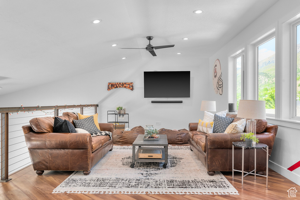 Living room featuring ceiling fan, vaulted ceiling, and light wood-type flooring