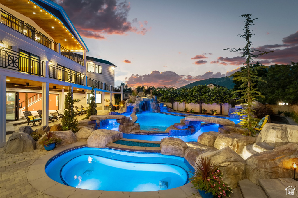 Pool at dusk with a patio area and pool water feature