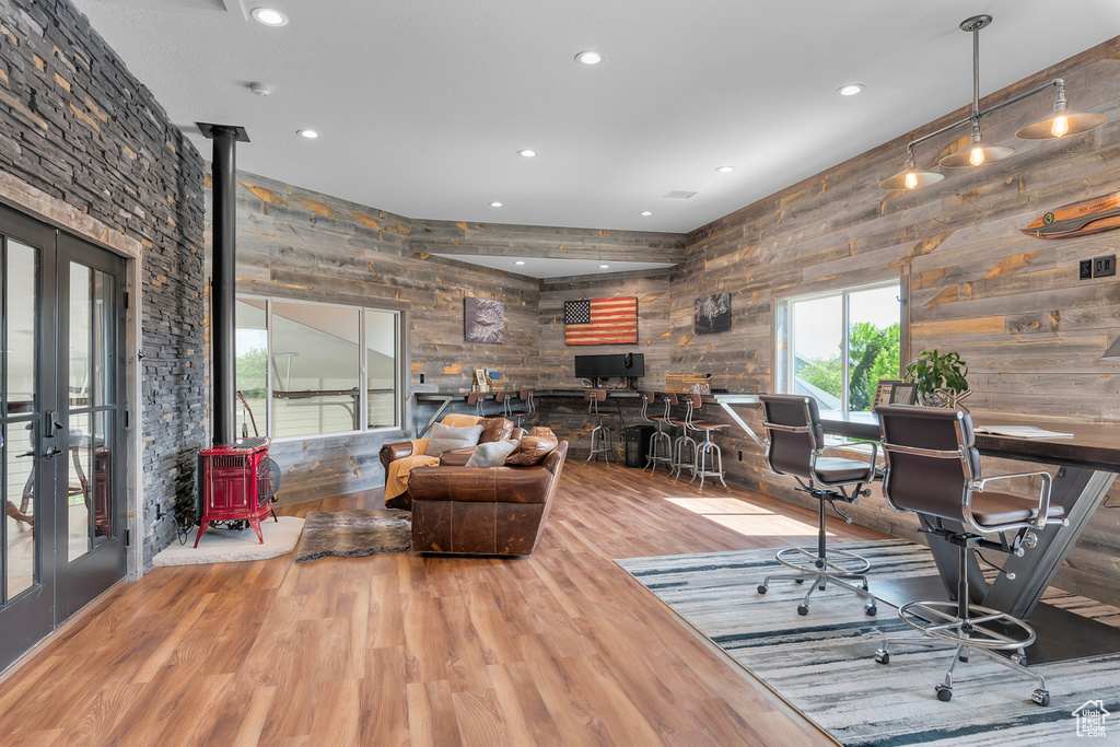 Office area with wooden walls, french doors, hardwood / wood-style floors, and a wood stove