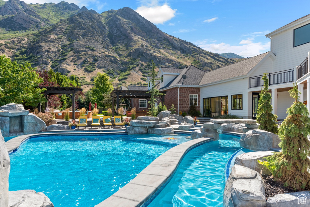 View of pool featuring pool water feature, a pergola, and a mountain view