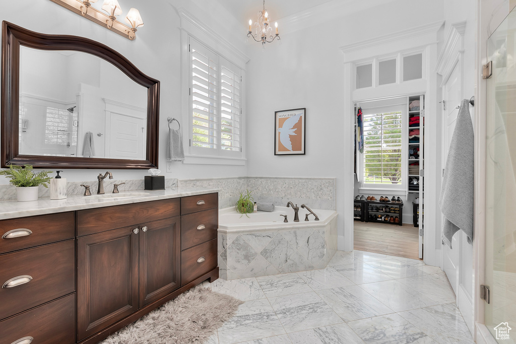 Bathroom featuring a chandelier, tile floors, crown molding, tiled bath, and vanity