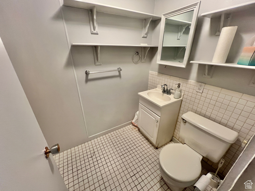 Bathroom with tile walls, backsplash, oversized vanity, toilet, and tile flooring