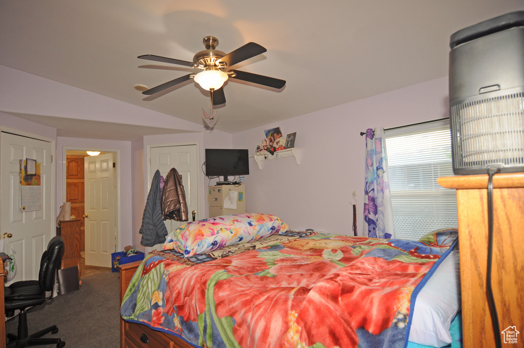 Bedroom with carpet floors, ceiling fan, and vaulted ceiling