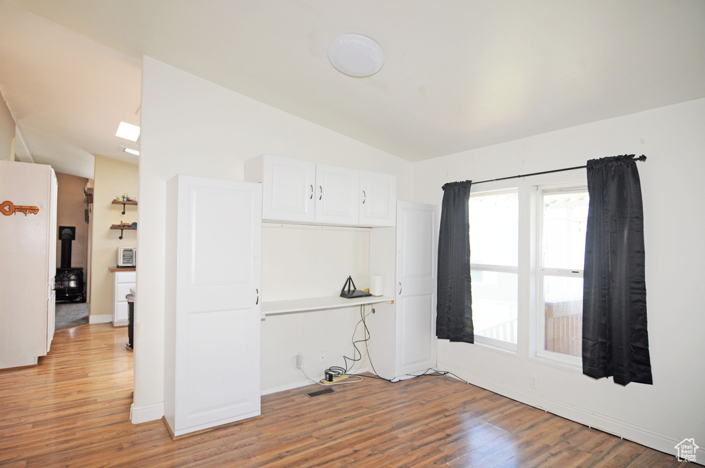 Spare room with a wealth of natural light, light wood-type flooring, and vaulted ceiling