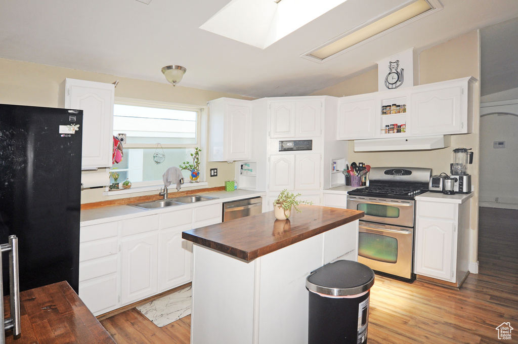 Kitchen featuring appliances with stainless steel finishes, sink, wood counters, and light wood-type flooring